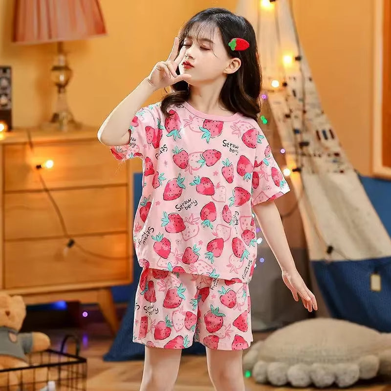 Girl wearing a strawberry design two piece pyjama set in a cosy environment