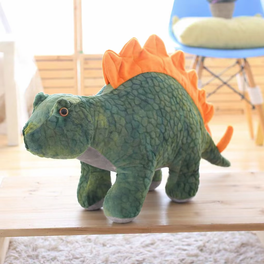Green soft plush stegosaurus dinosaur on a wooden surface in a living room setting.
