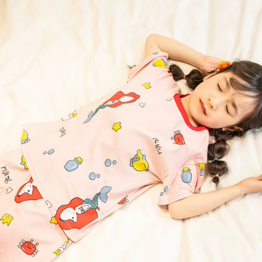 Child lying down wearing a mermaid design 2 piece pyjama set in a cosy setting