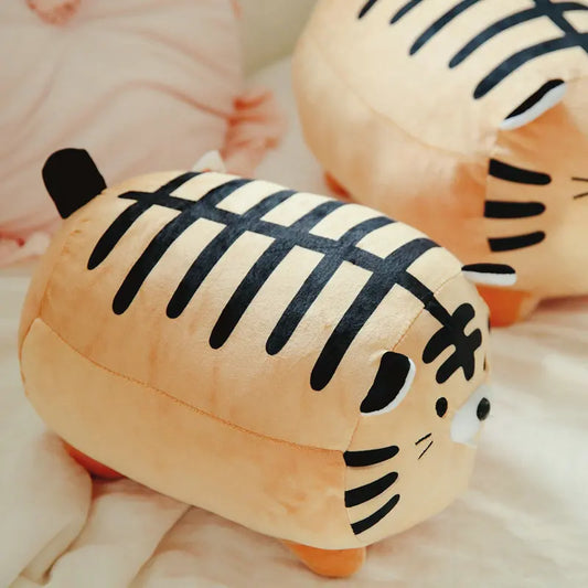 Two plush tiger toys with black stripes on a soft surface