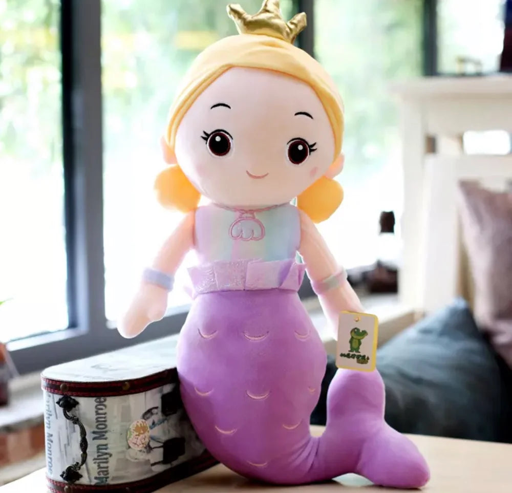 Plush toy mermaid with a crown on a table with a blurred background