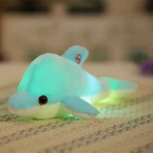 Blue soft plush light-up dolphin on a blurred surface.