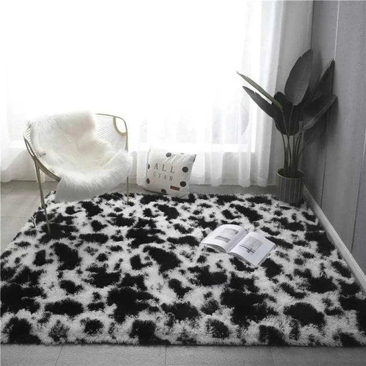 Black and white cow print rectangular plush rug placed on the floor in a cosy environment