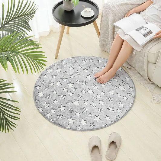 Round light grey kids rug with white star print placed on a light wood floor beside a sofa