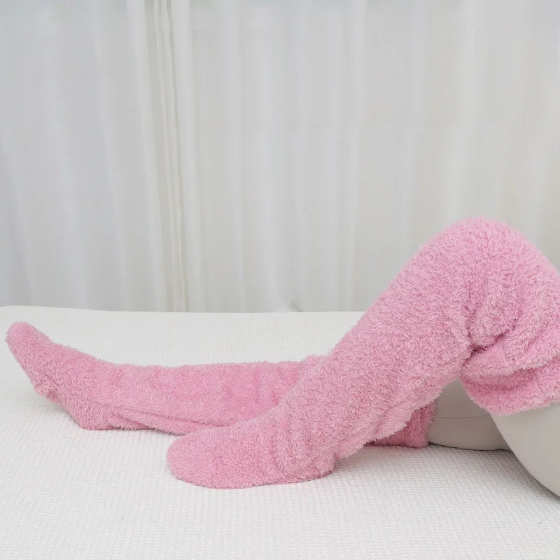 Pink fuzzy socks on a white surface with a neutral background