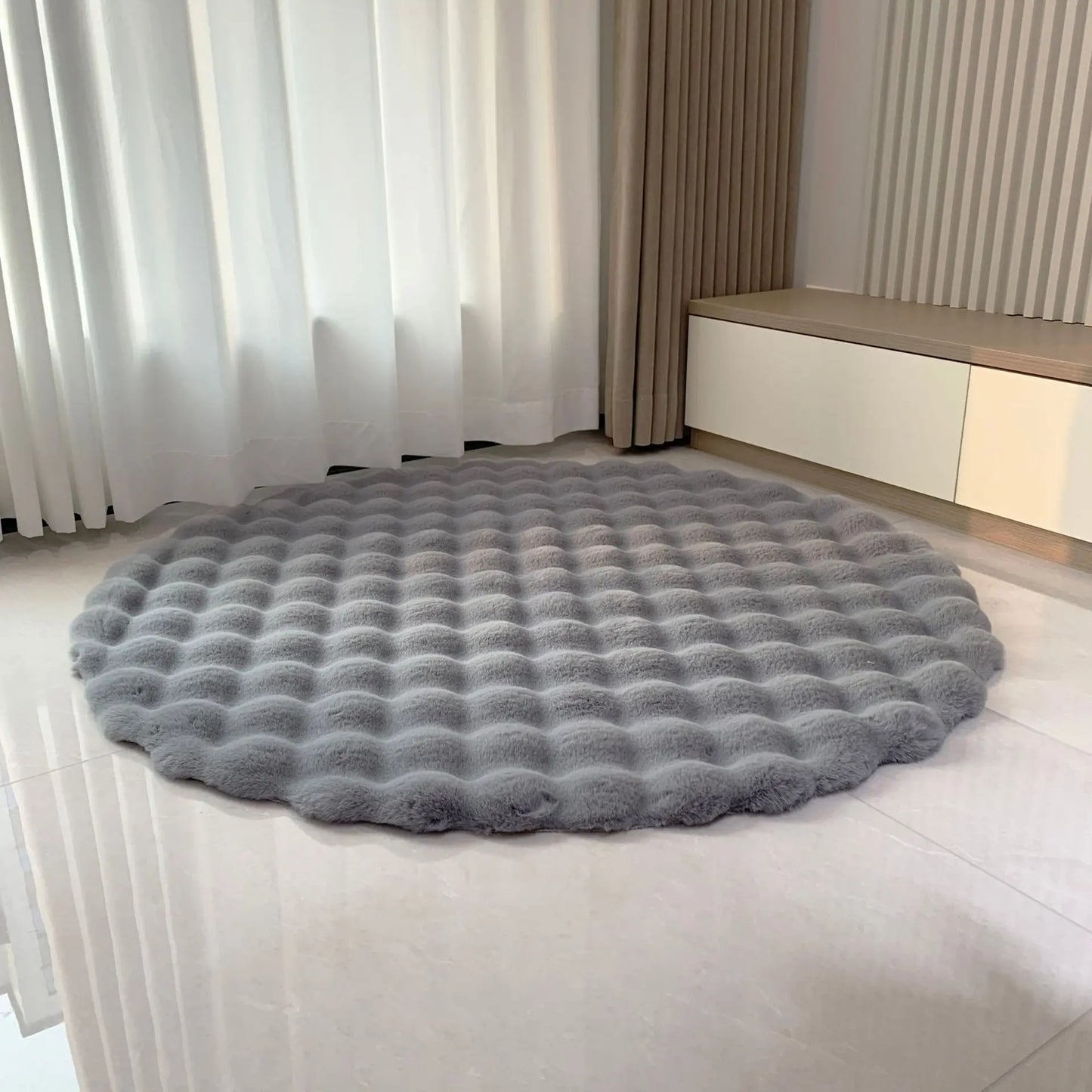 Grey round bubble velvet plush rug placed on a light floor in a softly styled room