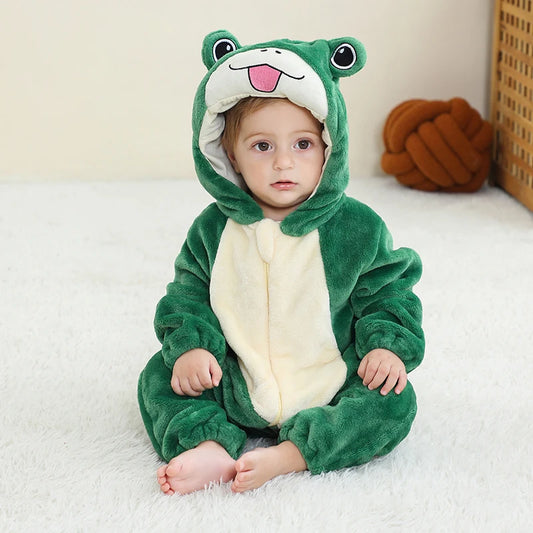 Child wearing a green frog onesie sitting on a white surface.