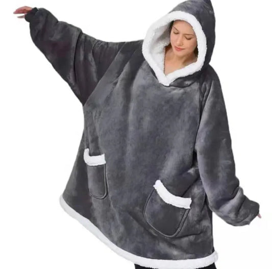 Woman wearing a grey thick oversized hoodie on a white background.