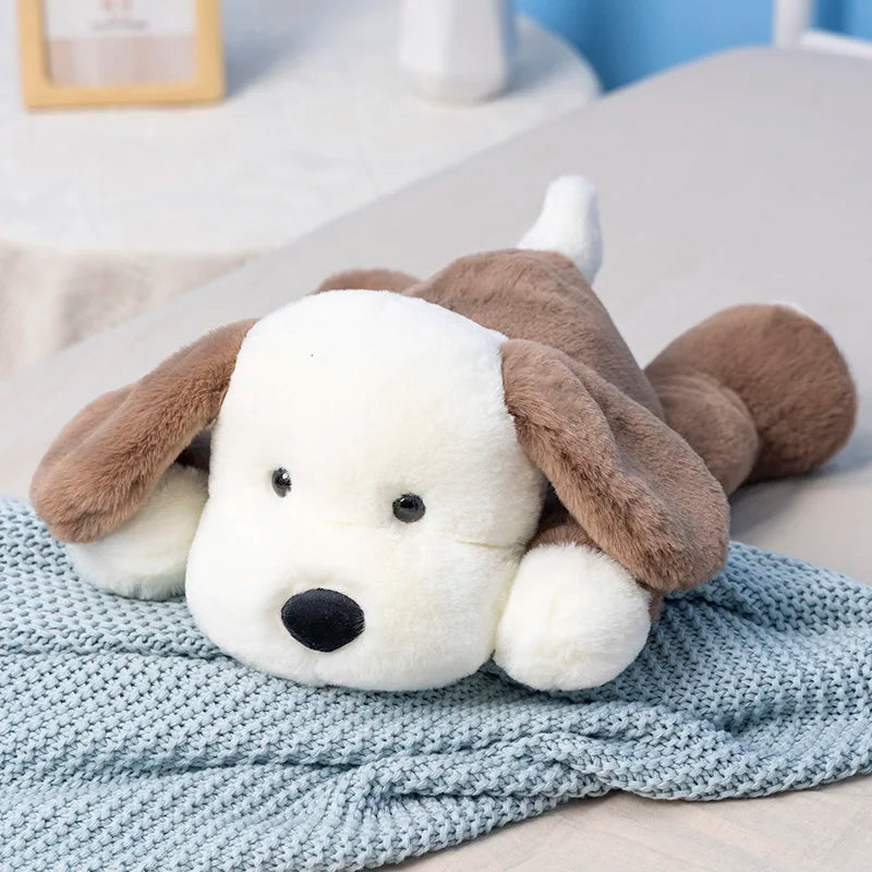 Brown and white puppy plush toy with floppy ears resting on a knitted blanket