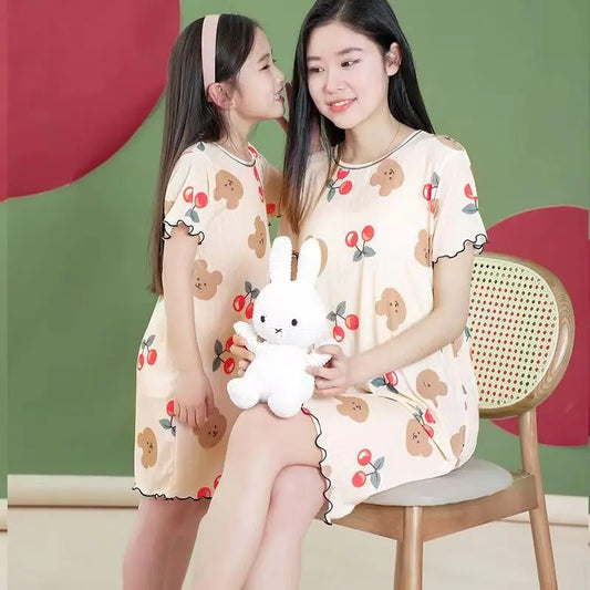 Two people wearing a cotton nightdress with cherry and bear print, short sleeves and above-the-knee length
