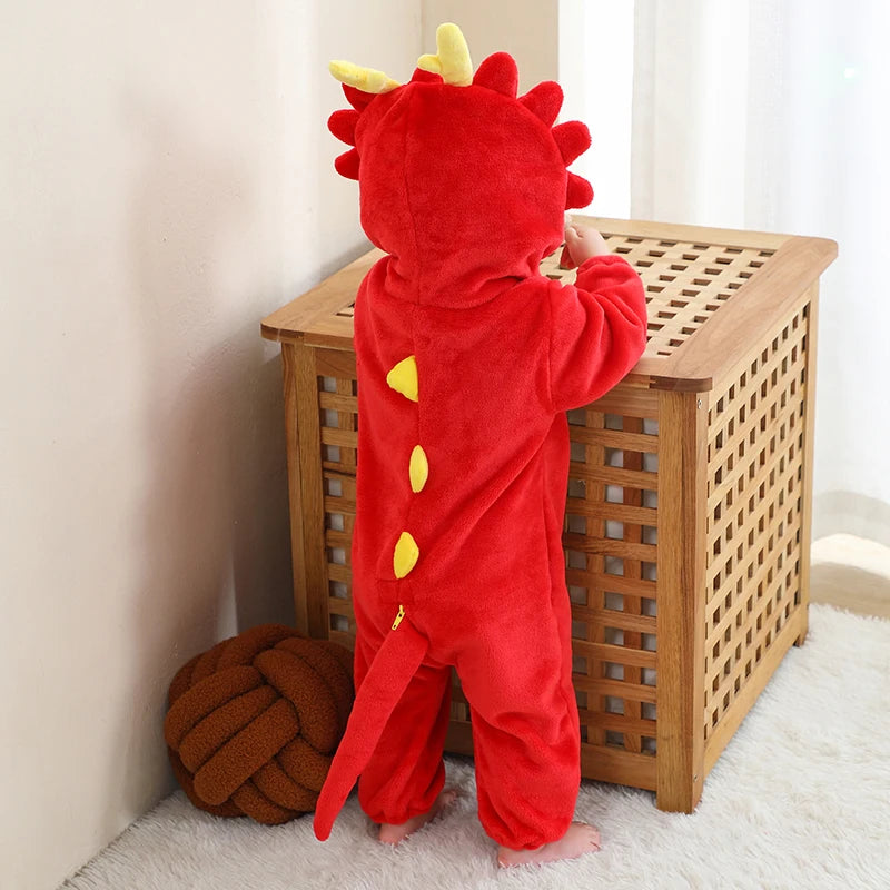Child wearing a red dinosaur onesie standing next to a wooden basket.