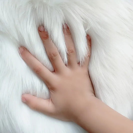 Hand resting on a white fluffy rug surface