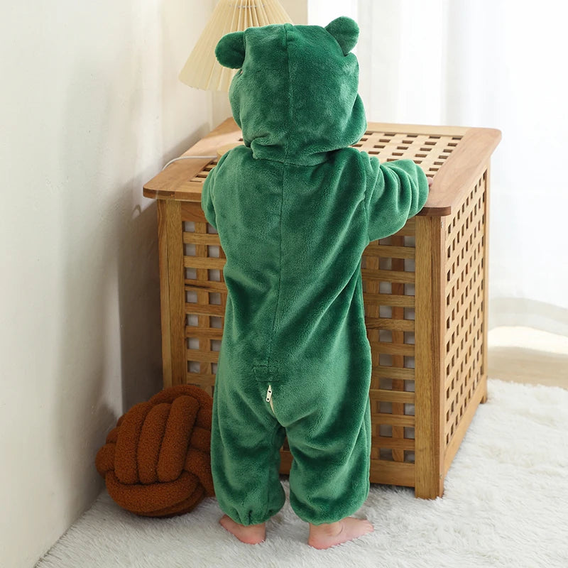 back view of a child wearing a green frog onesie in a cosy room