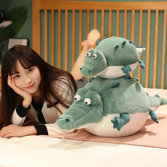 Woman lying on a bed with two green plush toys resembling crocodiles.