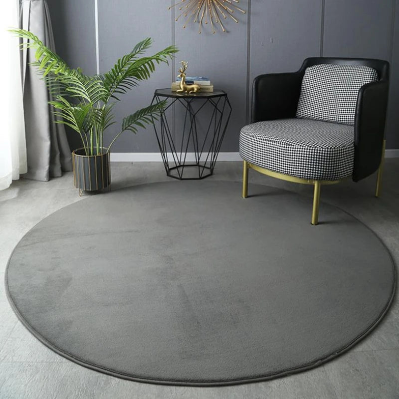 Round grey rug in a room with a chair, plant, and side table.