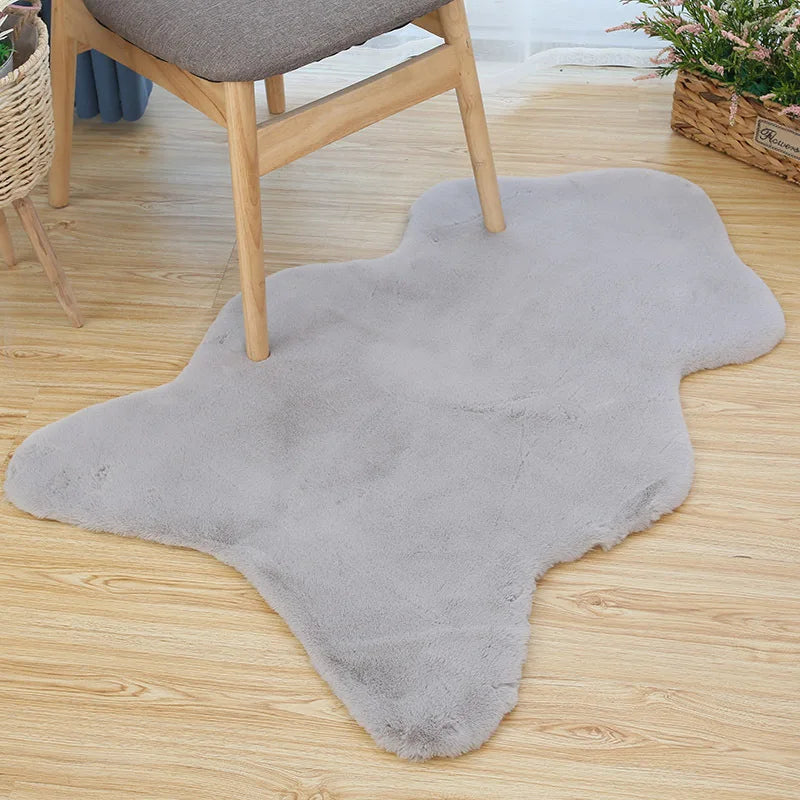Light grey fun-shaped faux rabbit fur rug placed on a wooden floor beneath a chair