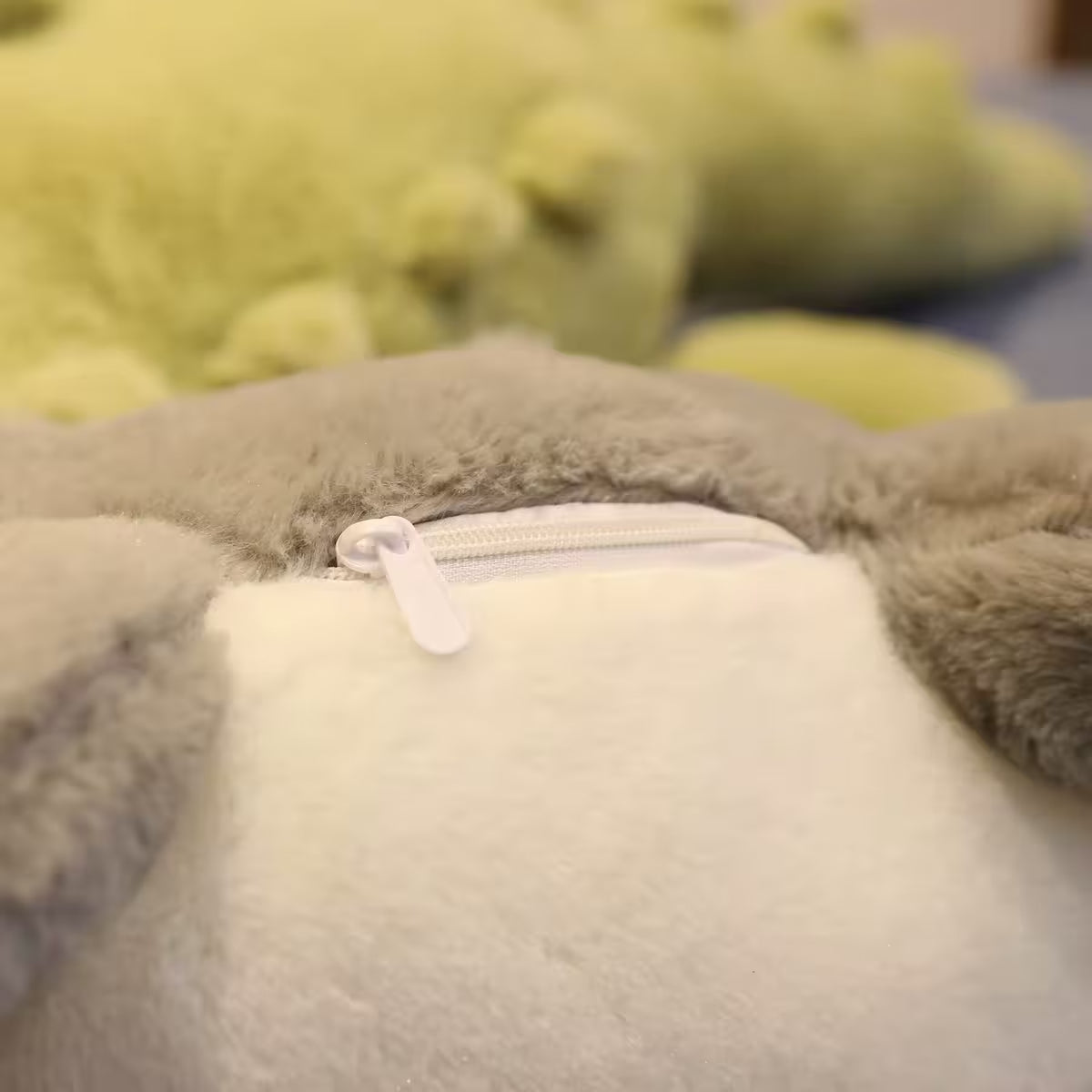 Close up of the closed zipper of a soft plush crocodile toy.