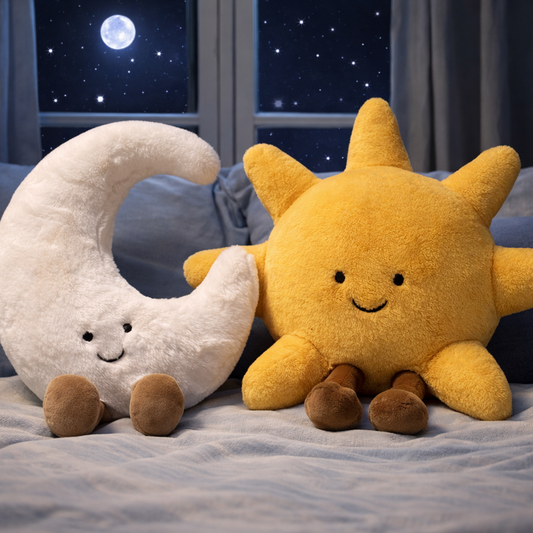 Sun and moon plush soft toys sat on a bed.