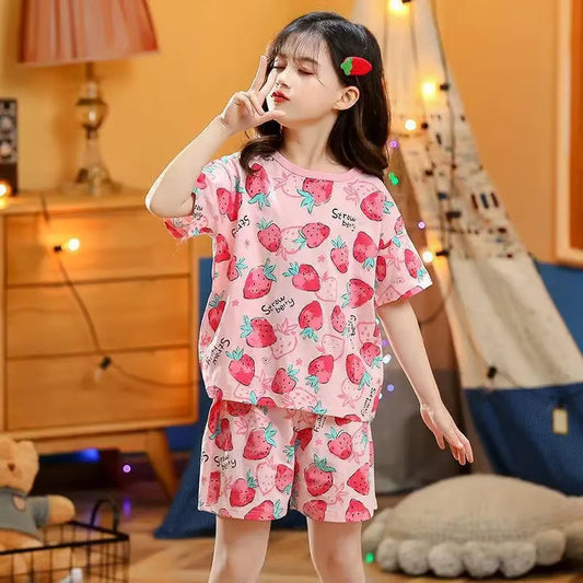 Girl wearing a strawberry design two piece pyjama set in a cosy environment