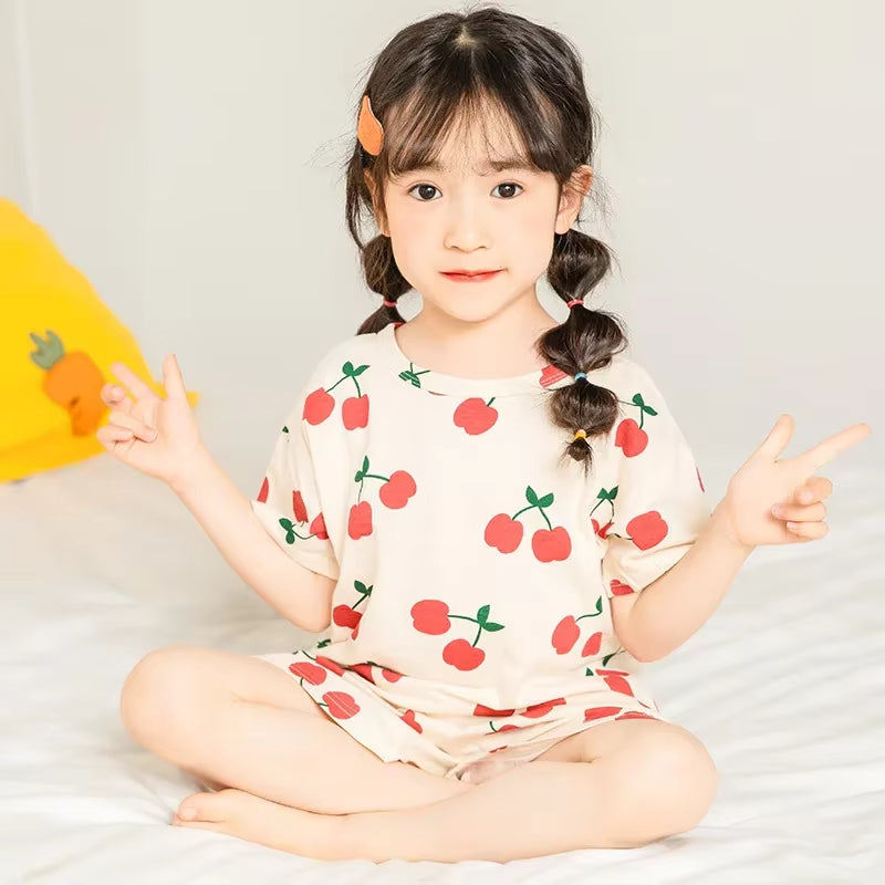 Child wearing a cherry print pyjama set in a cosy setting