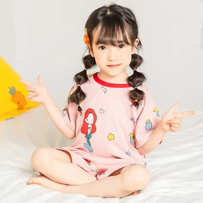 Child wearing a mermaid design 2 piece pyjama set in a cosy setting
