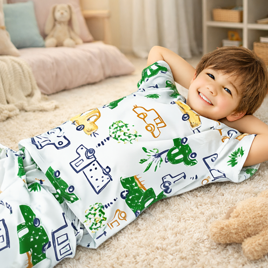 Child wearing vehicle pattern pyjamas on a carpeted floor.