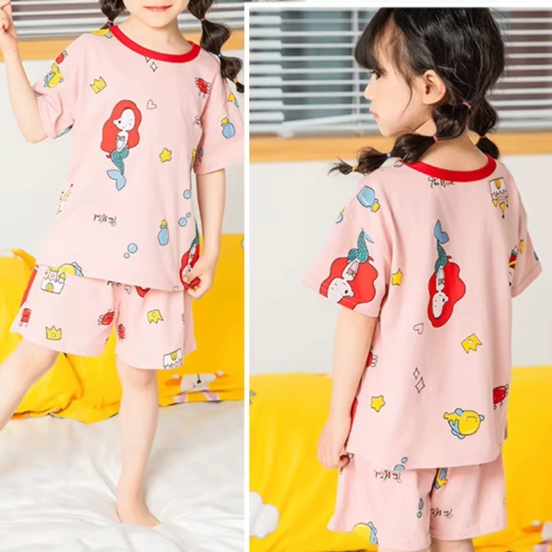 Front and back view of a child wearing a mermaid design 2 piece pyjama set in a cosy setting