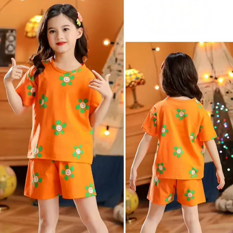 Front and back view of a girl wearing a cotton two-piece pyjama set with smiley flower print in a cosy settings
