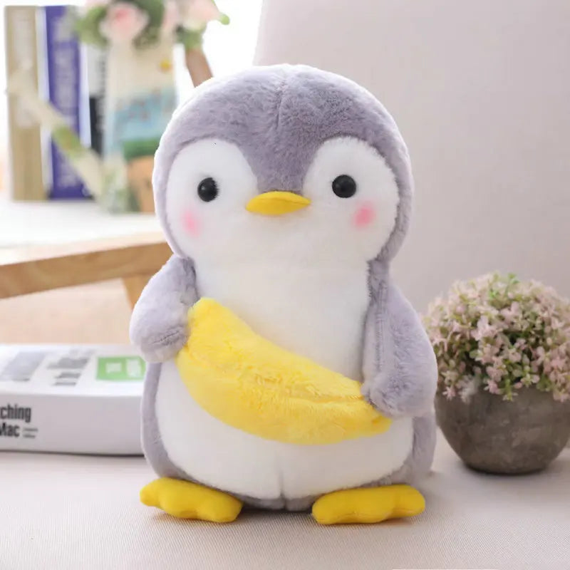 Stuffed penguin toy on a surface with a blurred background holding a banana.