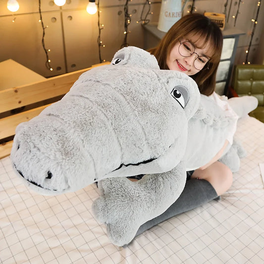Large grey soft plush crocodile toy being held by a woman.