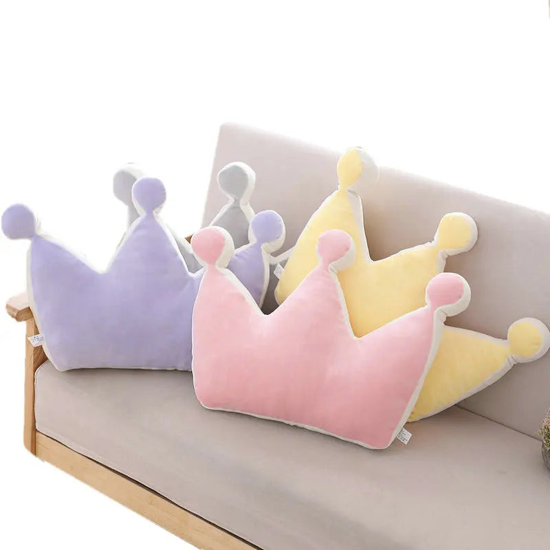 Three colorful crown-shaped cushions on a light-colored sofa.