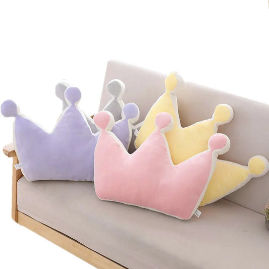 Three colorful crown-shaped cushions on a light-colored sofa.