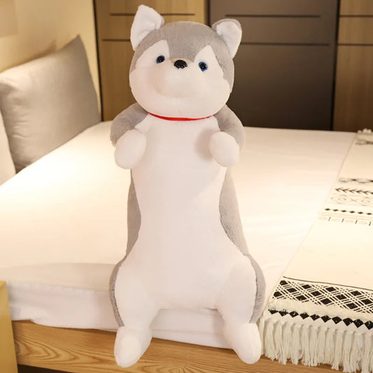 Plush toy husky sitting on a bed in a bedroom setting