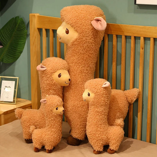 Four fluffy brown stuffed alpaca toys on a bed.