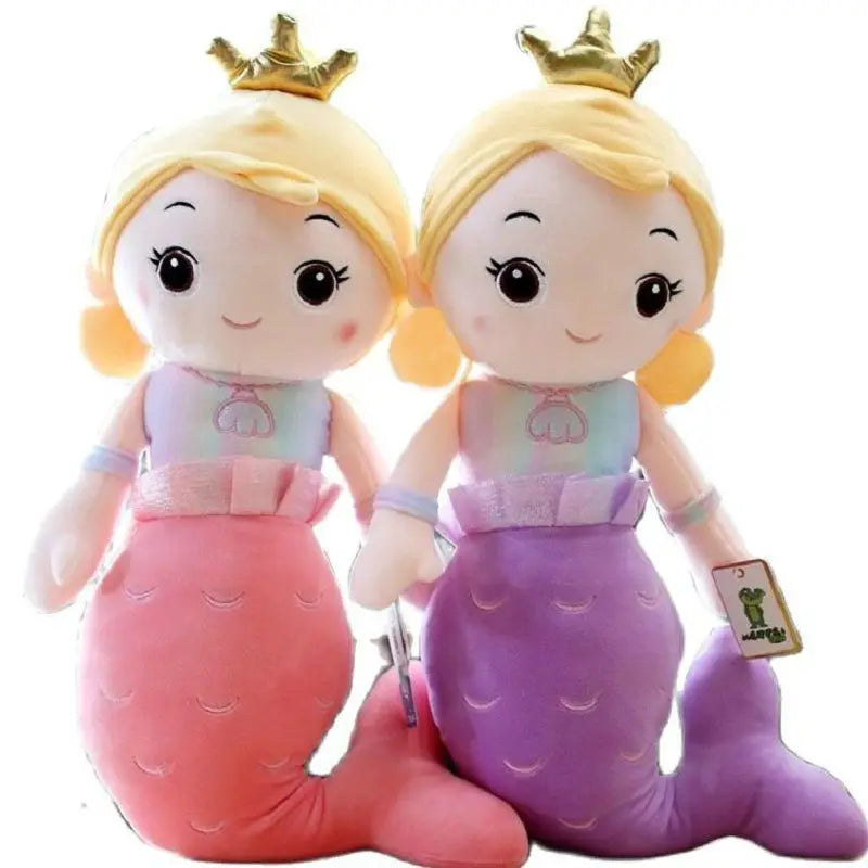 Two plush toys resembling mermaids with blonde hair and crowns on a white background.