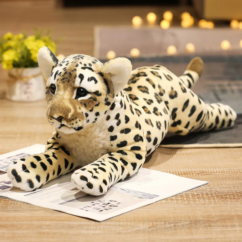Plush toy leopard lying on a newspaper with a blurred indoor background