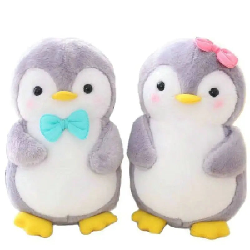 Two plush penguins, one with a bow tie and the other with a pink bow, on a white background.