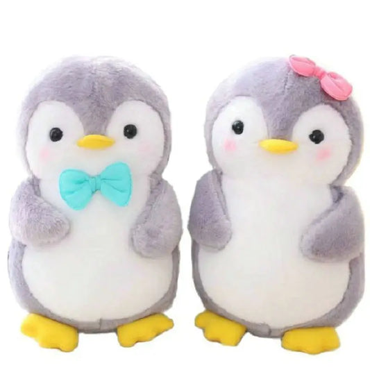 Two plush penguins, one with a bow tie and the other with a pink bow, on a white background.