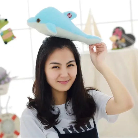 Woman holding a soft plush dolphin above her head with a blurred background.