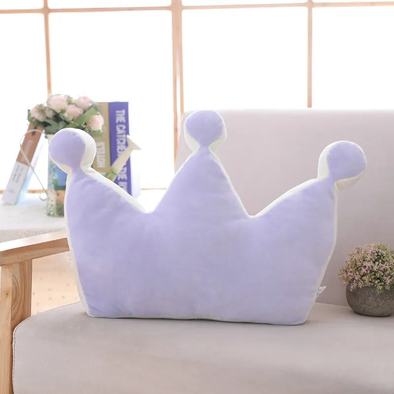 Purple plush crown pillow with soft rounded points displayed on a sofa