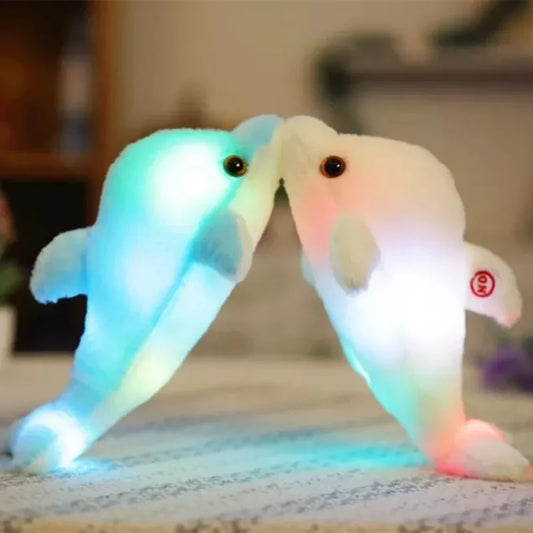 A pink and a blue light-up soft plush dolphin on a blurred background