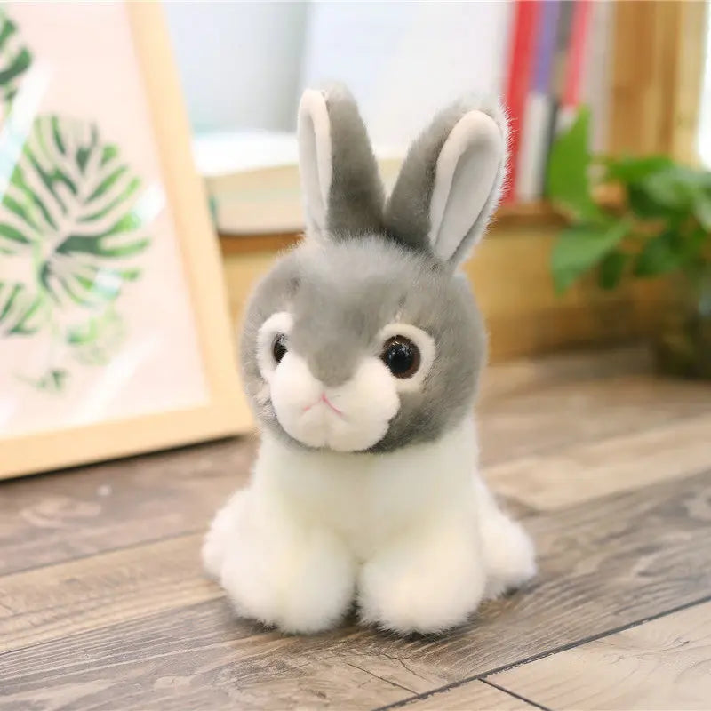 Plush grey and white toy rabbit on a wooden floor with a blurred background