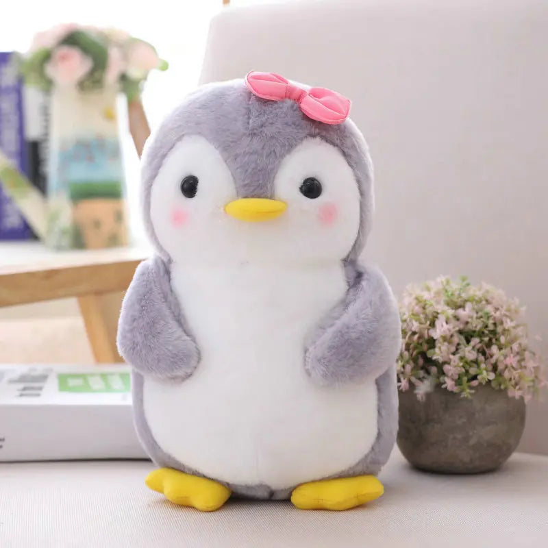 Plush toy penguin with a pink bow on a light background