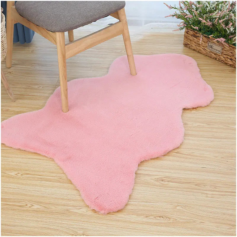 Pink fun-shaped faux rabbit fur rug placed on a wooden floor beneath a chair