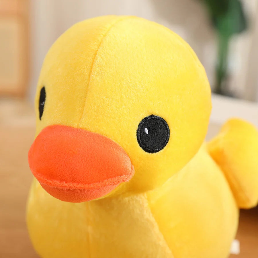Yellow duck plush toy with an orange beak and black eyes, shown in close-up with a soft plush finish