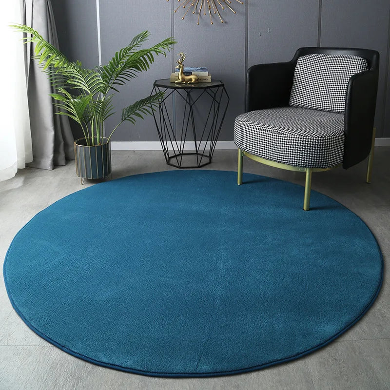 Round blue rug in a room with a black and white patterned chair, plant, and side table.