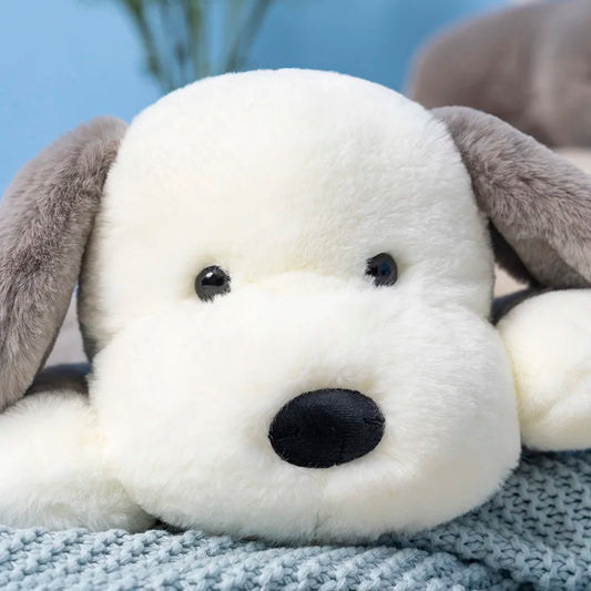 Close-up of a plush dog toy with a white face and gray ears on a textured surface.