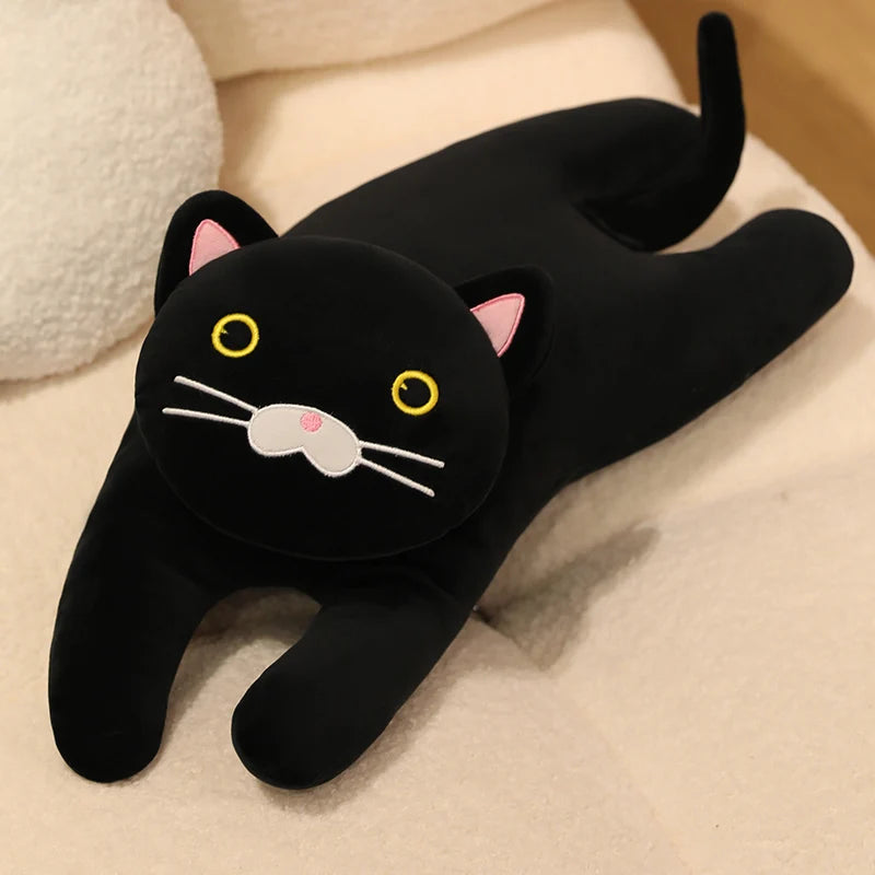 Black cat soft toy with yellow eyes and a long tail, stretched out on a cream sofa