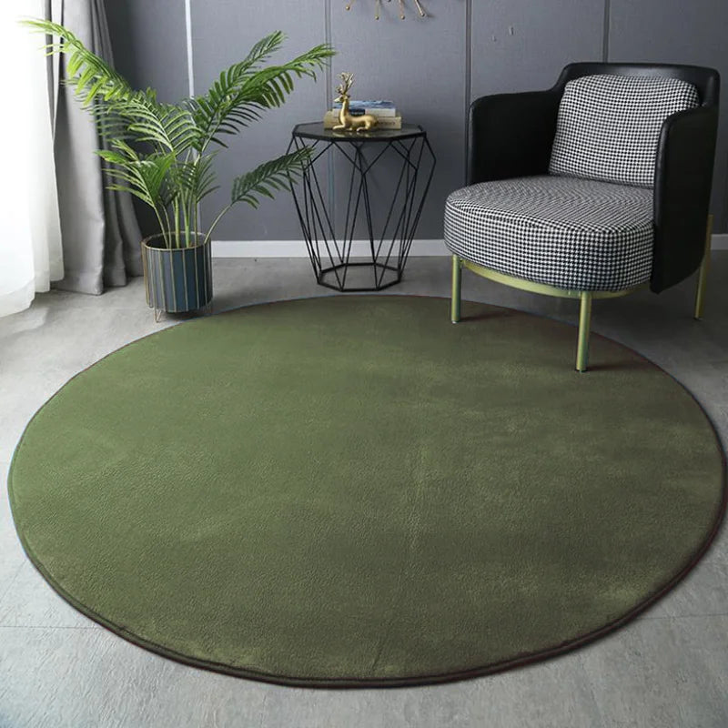Round green rug in a room with a black and white checkered chair, small table, and plant.