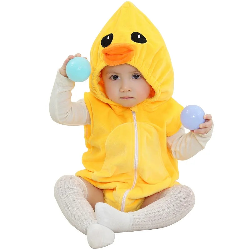 Baby wearing a yellow duck hooded onesie on a white surface. 